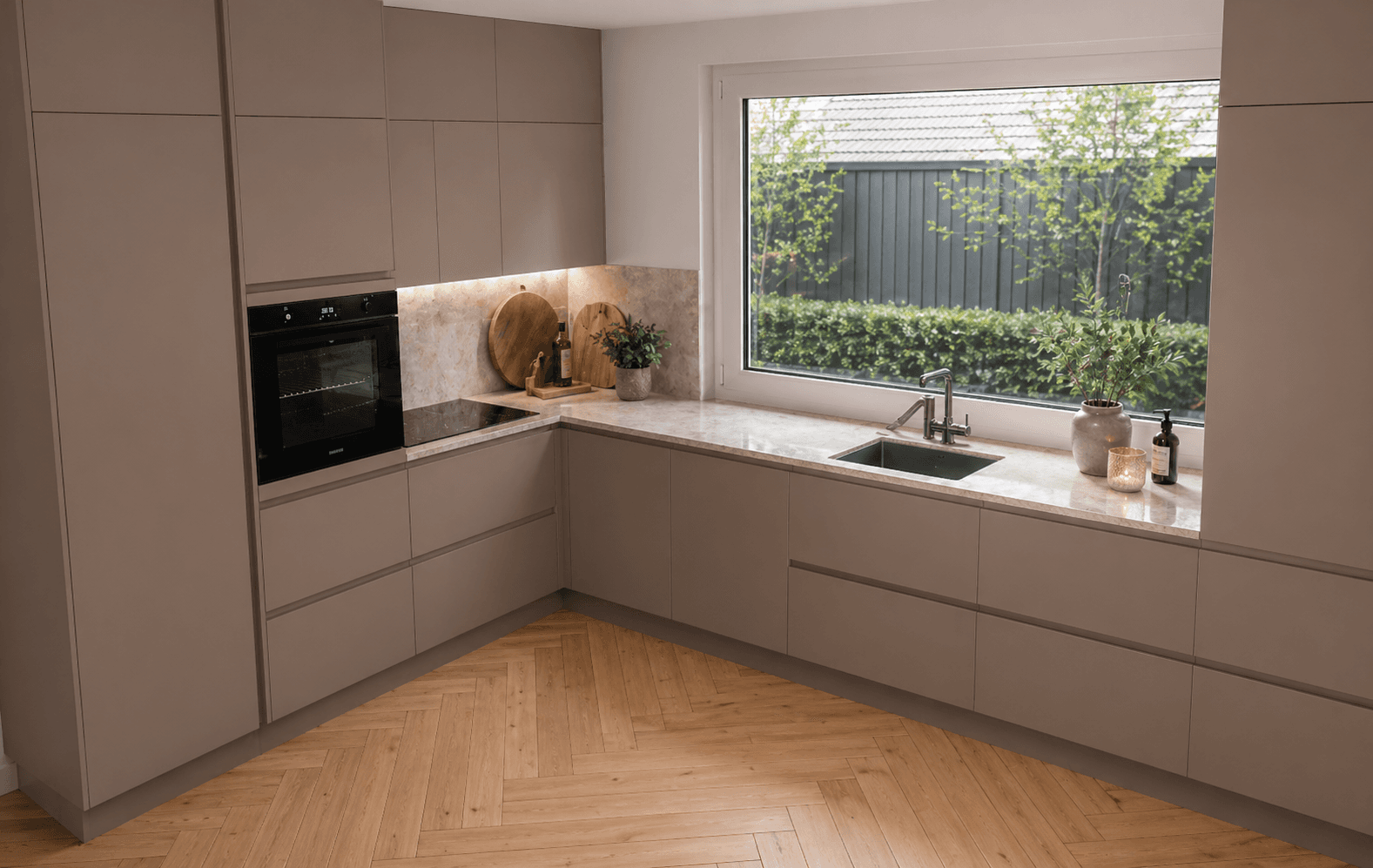 Taupe hoek keuken met marmeren achterwand en tuinzicht